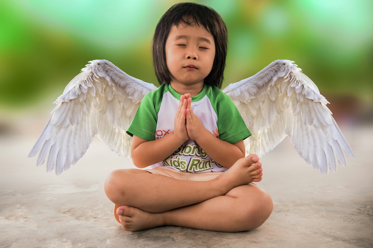 little girl in meditation pos with angel wings